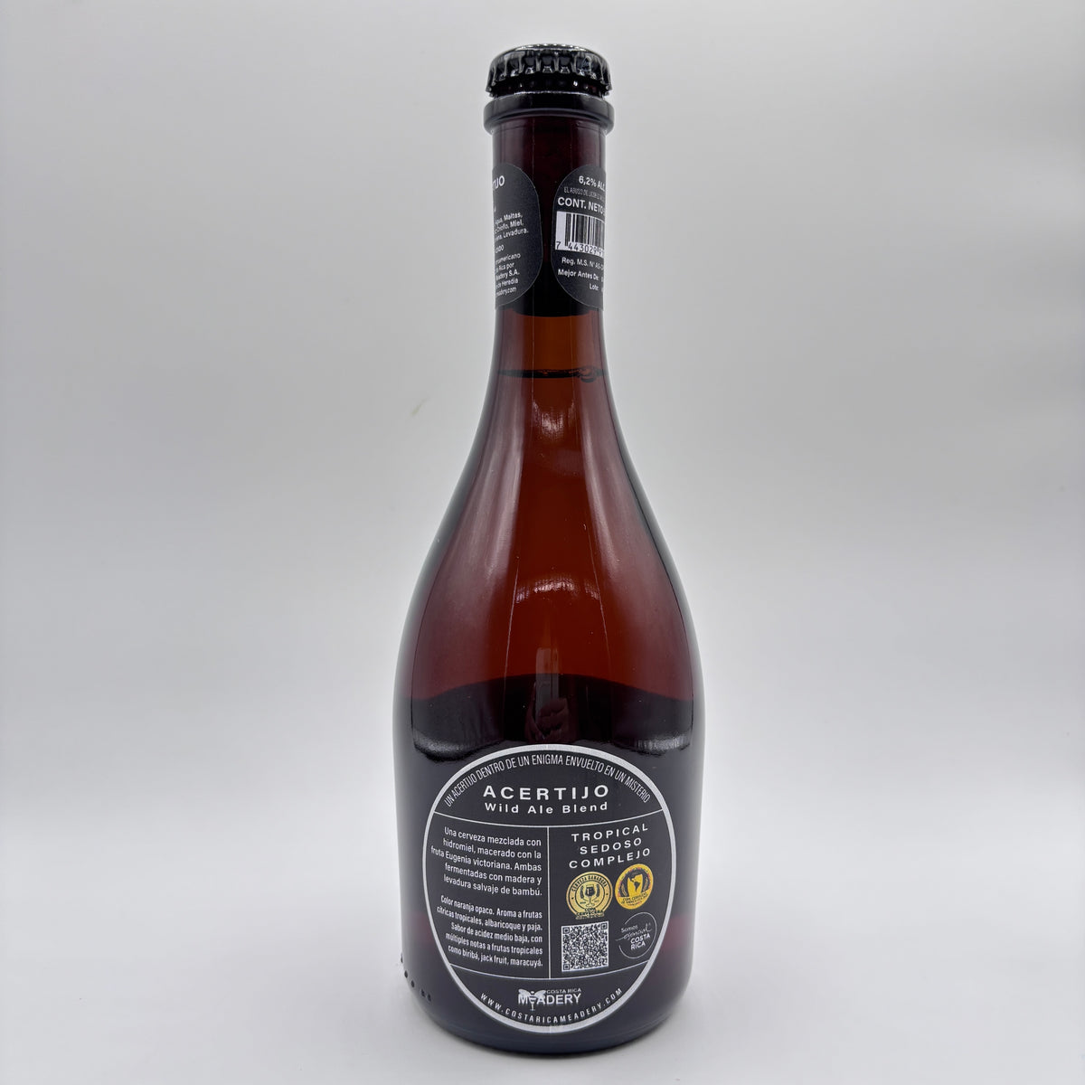 Botella de cerveza artesanal Acertijo Wild Ale Blend con etiqueta ovalada oscura sobre un fondo neutro.