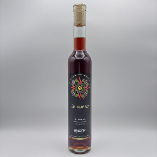 Botella estilizada de hidromiel Capsicao con etiqueta negra y diseño botánico sobre un fondo neutro.