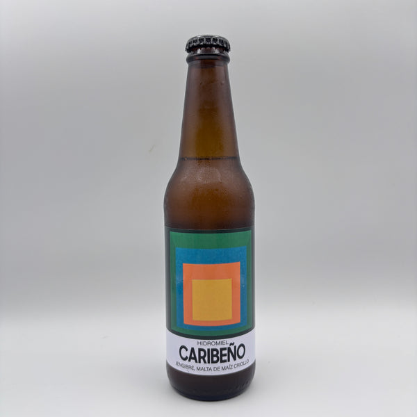 Botella de hidromiel Caribeño con jengibre y malta de maíz criollo, con diseño geométrico de colores en la etiqueta sobre un fondo neutro.