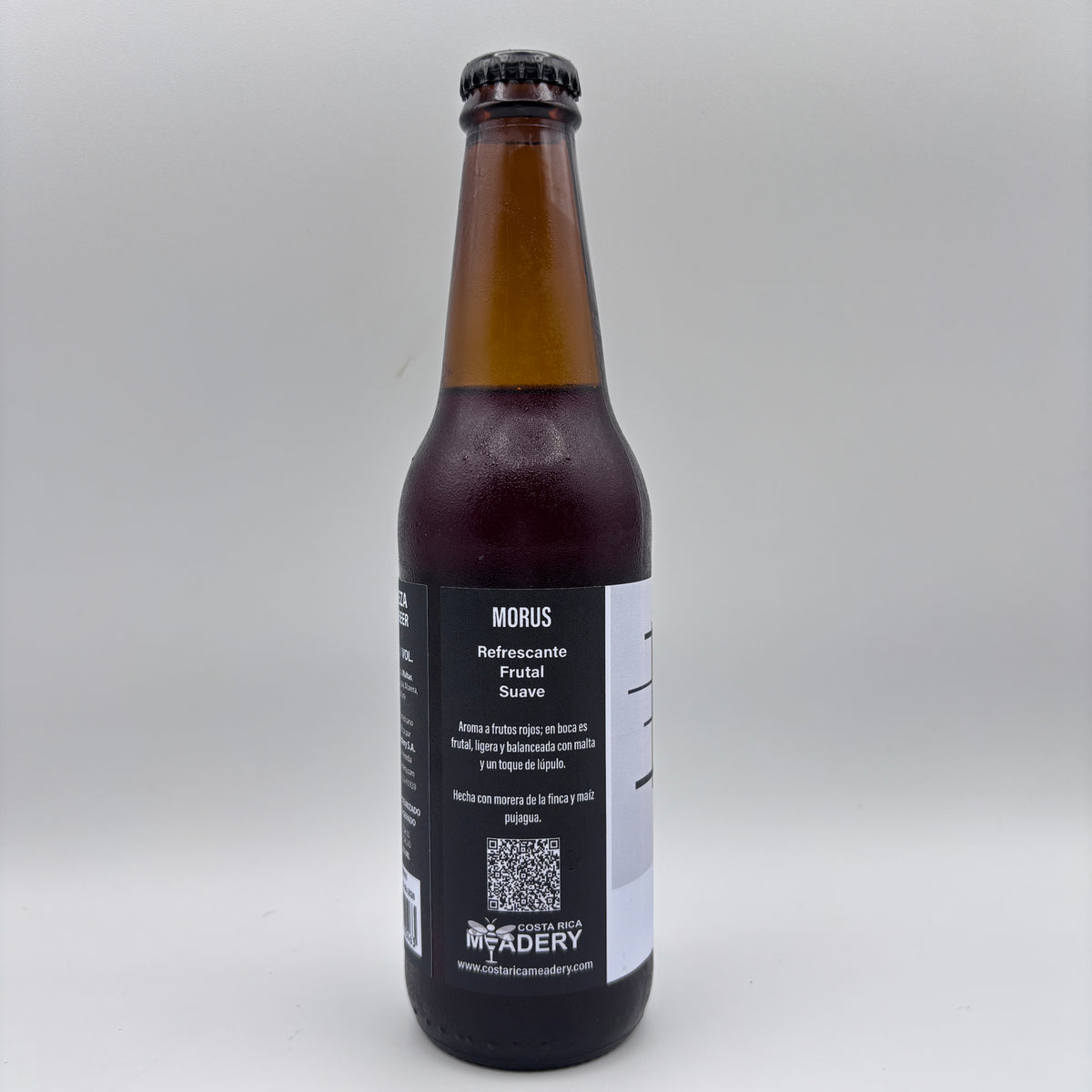 Vista lateral de la botella de Cerveza Morus mostrando en la etiqueta los descriptores Refrescante, Frutal y Suave, junto con el logo de Costa Rica Meadery y un código QR sobre un fondo neutro.
