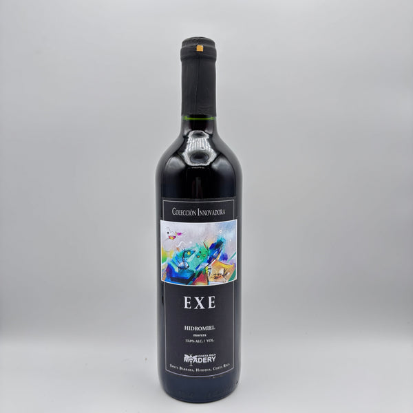 Botella de hidromiel Exe de la Colección Innovadora con etiqueta oscura e ilustración artística multicolor sobre un fondo neutro.