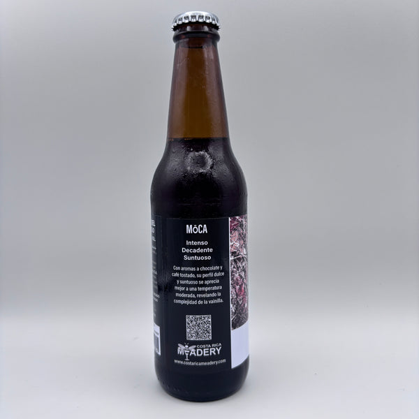 Vista lateral de la botella de hidromiel Möca mostrando en la etiqueta los descriptores Intenso, Decadente y Suntuoso, junto con el logo de Costa Rica Meadery y un código QR sobre un fondo neutro.