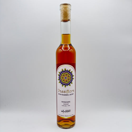 Botella estilizada de hidromiel Passiflora Rum Barrel-Aged con maracuyá, mostrando una etiqueta clara con un diseño mandálico multicolor y el logo de Costa Rica Meadery sobre un fondo neutro.
