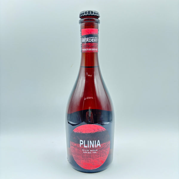 Botella de hidromiel Plinia Wild Mead con etiqueta circular de color rojo que indica 8.0% Alc/Vol y banda de Costa Rica Meadery en el cuello sobre un fondo neutro.